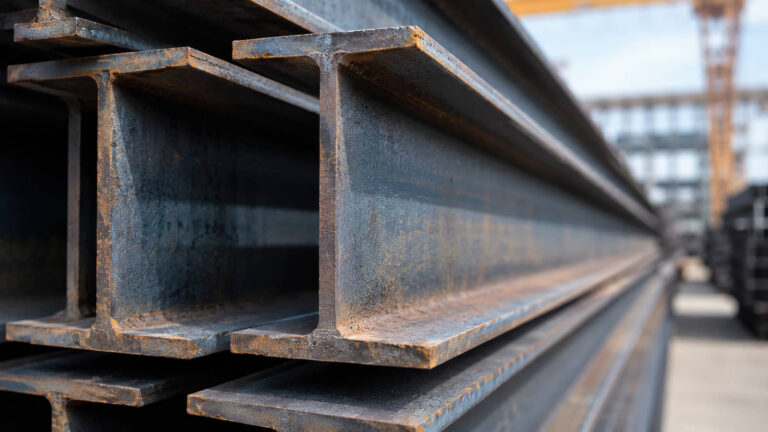 Stacked steel I-beams at a construction site.