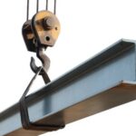 Crane hook lifting a steel I-beam.