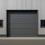 Industrial metal building with a large gray roll-up door and two small windows.