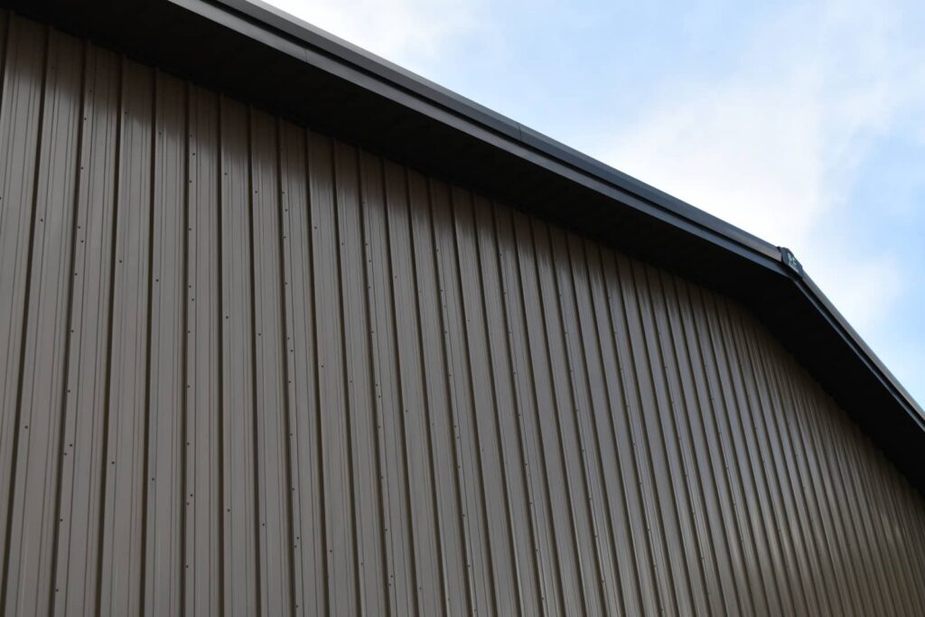 Corrugated metal building wall and roofline against a blue sky.