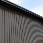 Corrugated metal building wall and roofline against a blue sky.