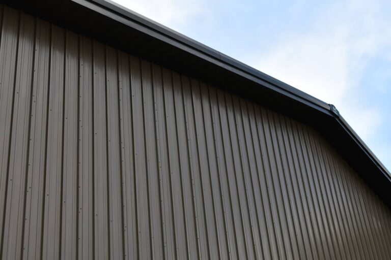 Corrugated metal building wall and roofline against a blue sky.